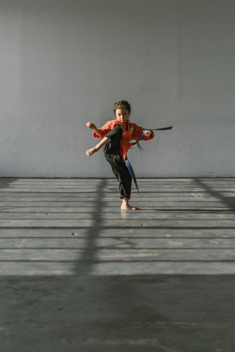 boy in red t shirt and black pants jumping on gray wooden floor
